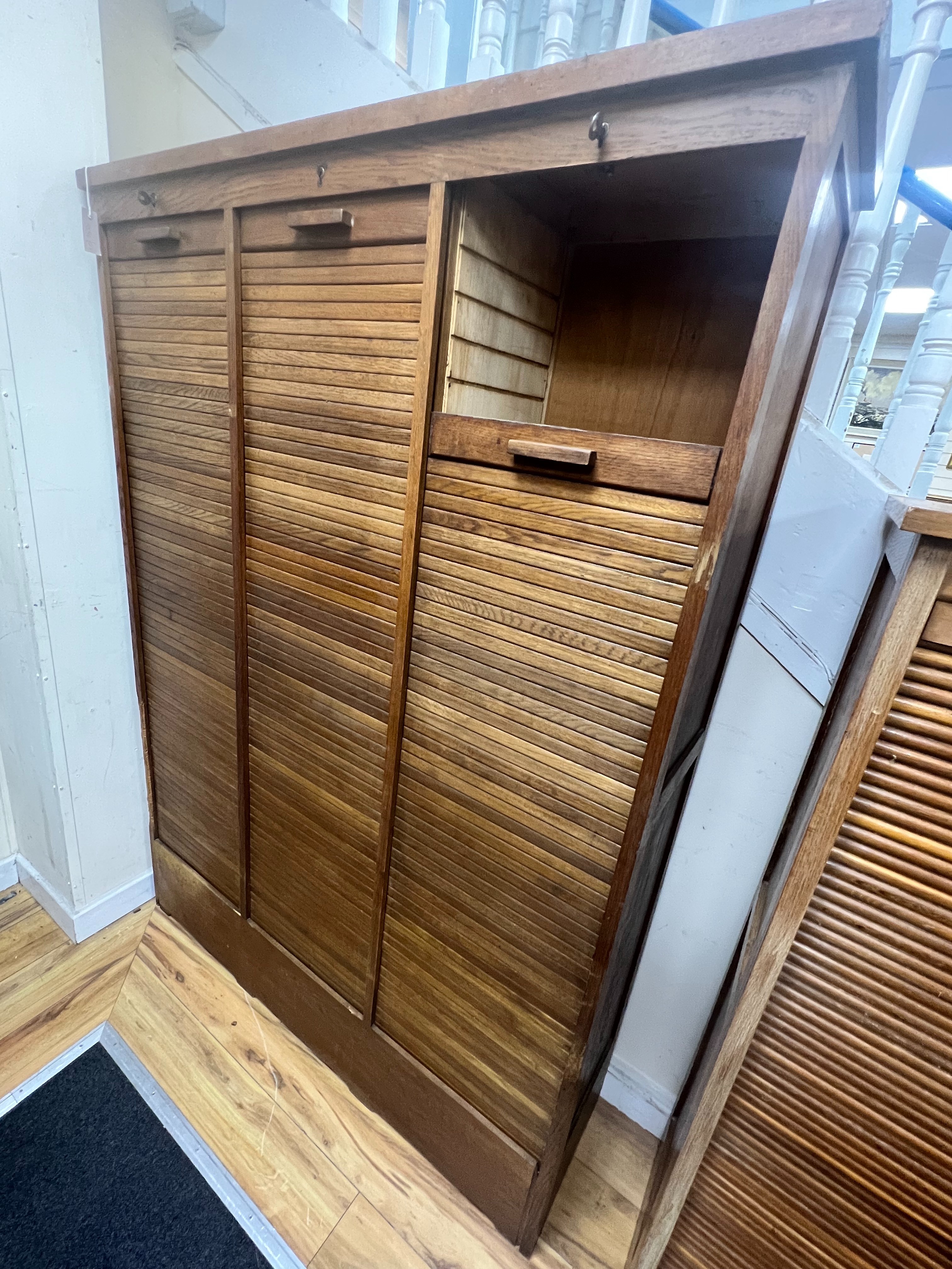 A mid century oak triple tambour filing cabinet, width 129cm depth 37cm height 180cm